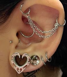 a woman wearing ear piercings with chains and heart shaped earrings on her left side