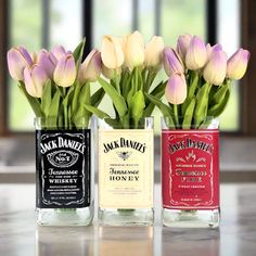 three vases with flowers in them sitting on a table