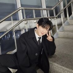 a young man in a suit sitting on the steps with his hand up to his face