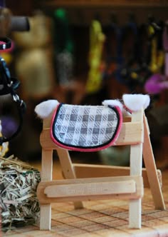 a small wooden rocking horse next to a pile of hay