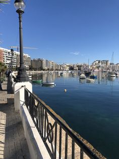 boats are docked in the water next to a light pole and railing on a sunny day