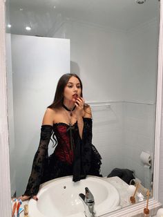 a woman standing in front of a bathroom mirror brushing her teeth