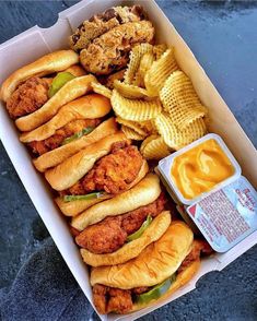 a box filled with fried chicken sandwiches and waffles next to potato wedges