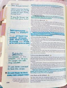 an open bible with blue and green writing on the pages, next to a pink blanket