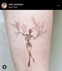 a woman's leg with a skeleton and flowers tattoo on it