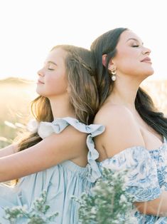 two women in blue dresses standing next to each other with their arms around one another