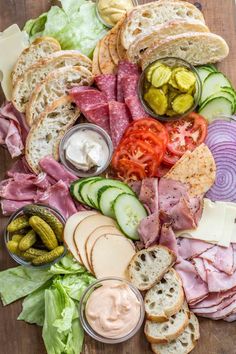 an assortment of meats, cheese and vegetables on a cutting board with pickles