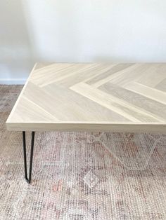 a coffee table with hairpin legs on carpeted flooring in front of white wall