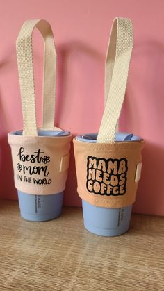 two coffee cups sitting next to each other on top of a wooden table in front of a pink wall