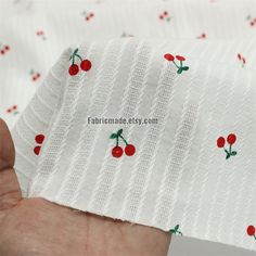 someone is holding some fabric with cherries on it