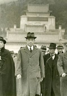 an old black and white photo of men in coats, hats and ties standing together