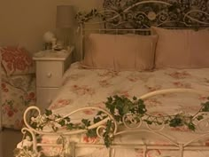 a white iron bed with pink flowers and vines on the headboard, in a bedroom