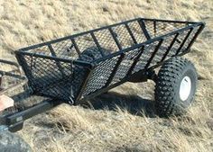 a man is pulling a cart with two large tires on the side of a field