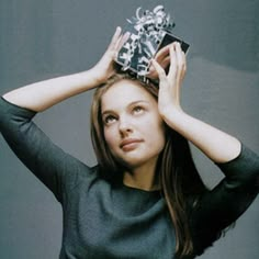 a woman is holding her hair in the air with one hand and wearing a tiara on top of her head