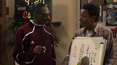 two young men standing next to each other in front of a white board with numbers on it