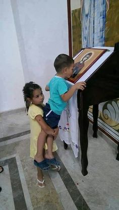 two young children are playing with a piano