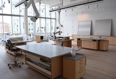 an empty office with lots of desks and chairs in front of large windowed windows