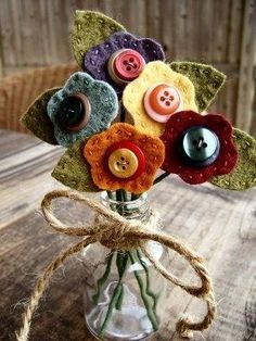 a vase filled with buttons and flowers on top of a wooden table