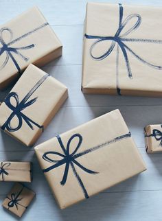 four wrapped presents are sitting on the floor next to each other, tied with blue ribbon