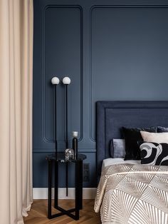 a bedroom with blue walls and wooden flooring, two lamps on each side of the bed