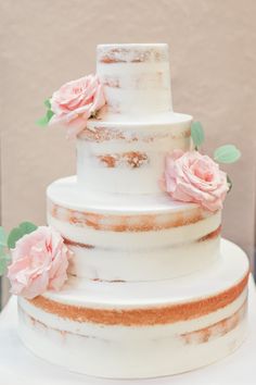 a three tiered white cake with pink flowers on top