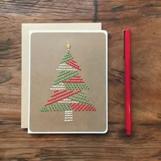 a christmas tree made out of colored pencils next to a notepad on a wooden table