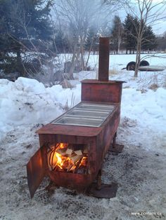 an open fire pit sitting on top of snow covered ground