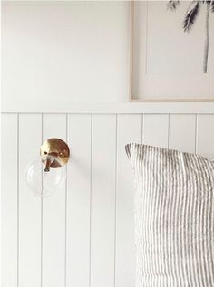 a bedroom with white walls, striped pillows and a gold door handle on the wall