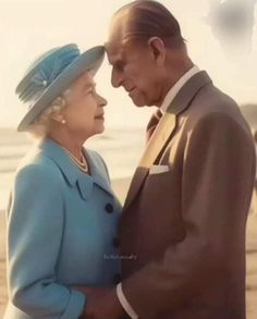 an older man and woman standing next to each other on top of a sandy beach