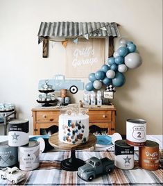 a table topped with cake and balloons next to other items on top of a checkered table cloth