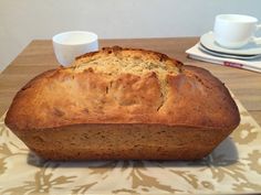 a loaf of bread sitting on top of a table next to two cups and saucers