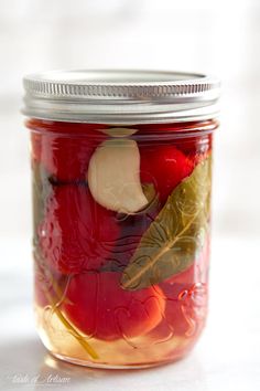 a glass jar filled with pickled cherries and apples