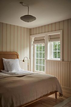 a bed sitting next to two windows in a bedroom