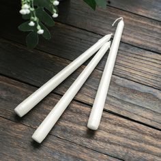 three white candles sitting on top of a wooden table