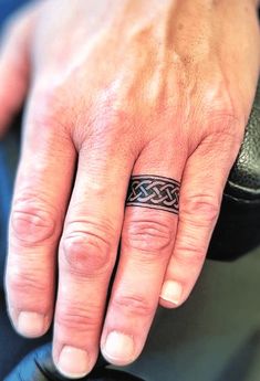 a man's hand with a ring tattoo on his left thumb and the middle finger