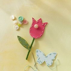 a paper flower and some buttons on a yellow surface with white fabric behind the flowers