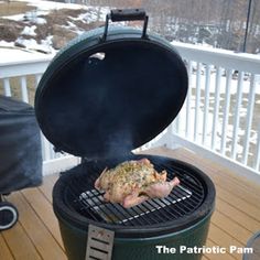 a grill with some meat on it sitting on a deck next to a snow covered hill