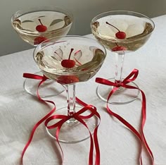 three martini glasses with cherries and ribbons