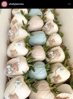 a box filled with lots of white chocolate covered in blue and pink frosted decorations