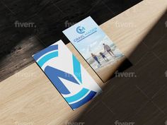 two business cards sitting on top of a surfboard next to each other in front of a wooden plank