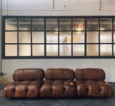 a brown leather couch sitting in front of a window