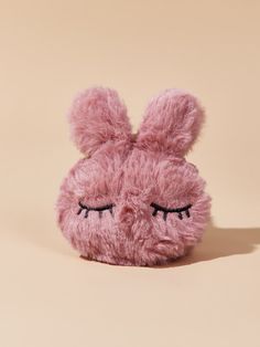 a pink stuffed animal with eyes closed and eyelashes on it's face, sitting in front of a beige background