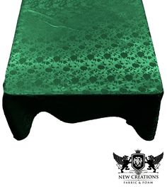 a green table cloth on top of a white surface with black trimming and an ornate design