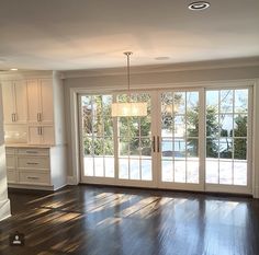 an empty living room with wood floors and sliding glass doors that lead out to the backyard