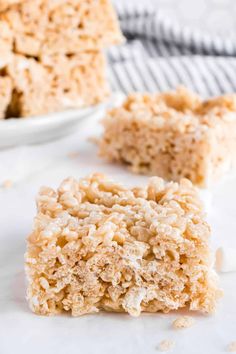 two pieces of rice krispy treats sitting on top of a white counter next to a bowl