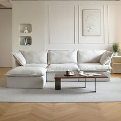 a white couch sitting on top of a wooden floor in a living room next to a coffee table