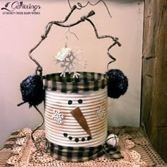 a snowman tin can sitting on top of a table next to a wooden sign