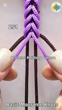 two hands are holding the ends of a purple and black macrame knot