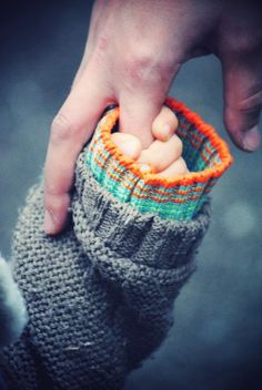 a person holding onto a pair of knitted mitts with the words tods vien a nuestra via para daros ora opotunidad