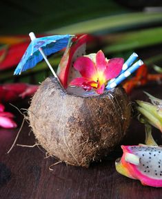 a coconut with flowers and umbrellas sticking out of it's side on a table